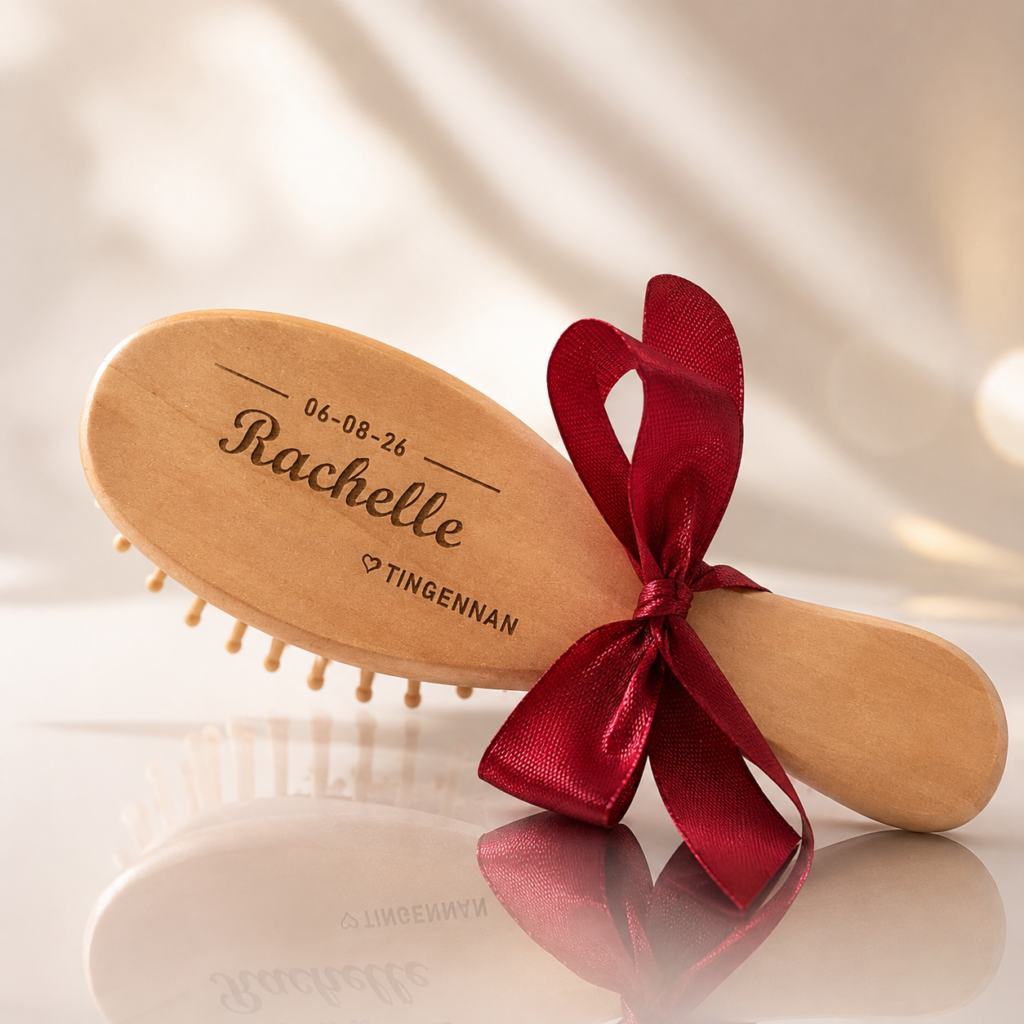 Engraved wooden hairbrush personalized with a name and date, tied with a red ribbon